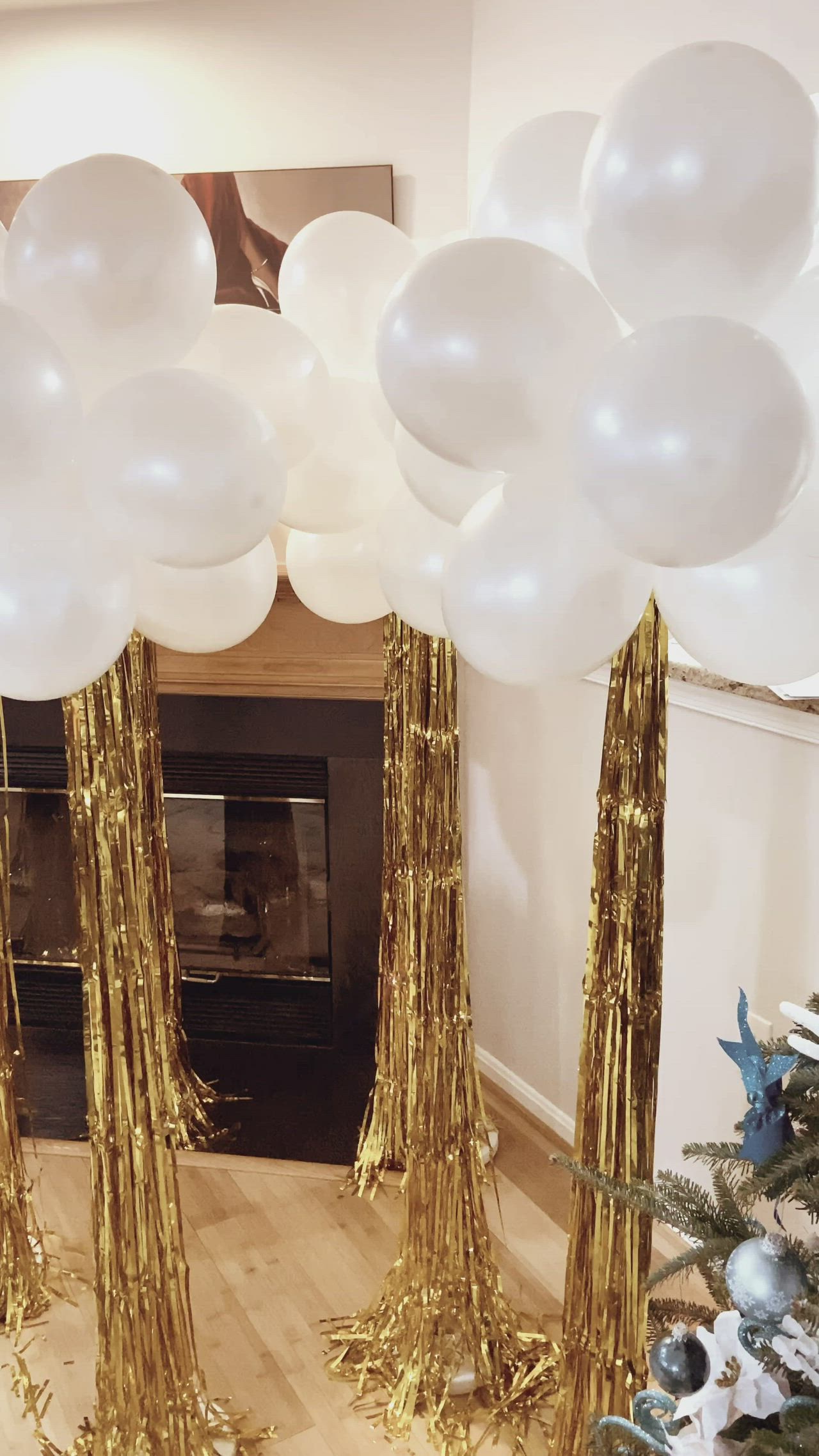 This may contain: white and gold balloons in front of a fireplace