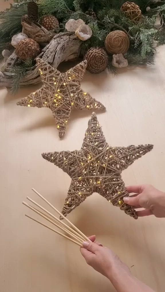 This may contain: someone is decorating two star shaped ornaments with candlesticks and pine cones on the table