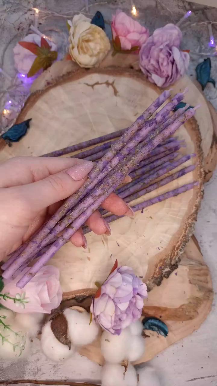 This may contain: a person holding purple flowers on top of a piece of wood next to cotton balls