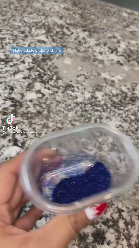 This may contain: a hand holding a plastic container filled with blue liquid on top of a countertop