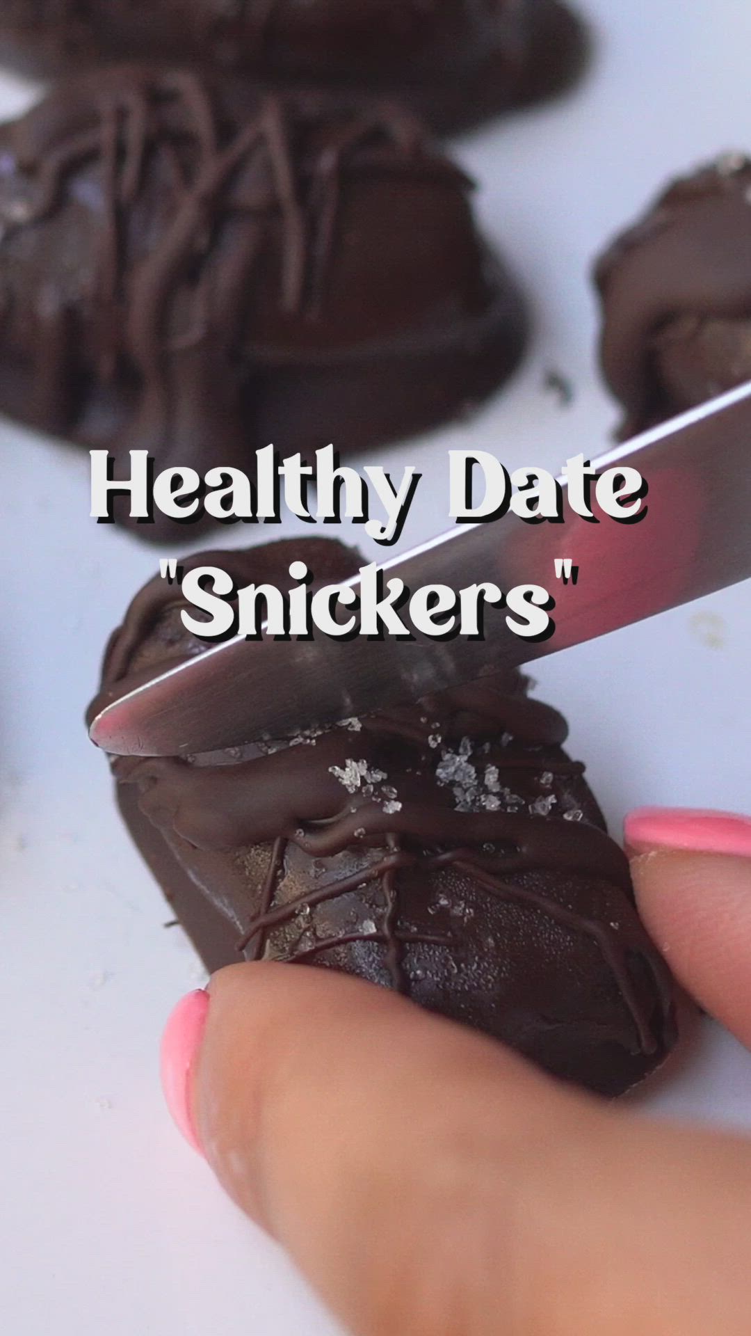 This may contain: a hand holding a piece of chocolate with the words healthy date snickkers on it