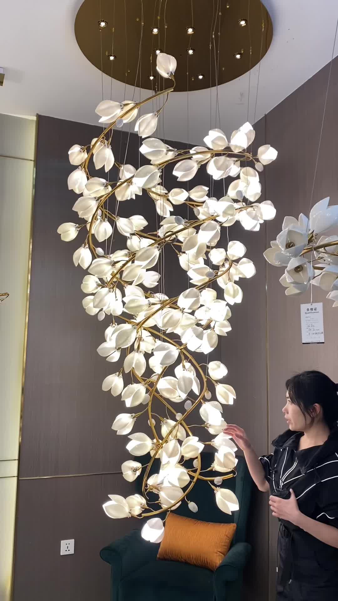 This may contain: a woman standing in front of a chandelier with white flowers hanging from it