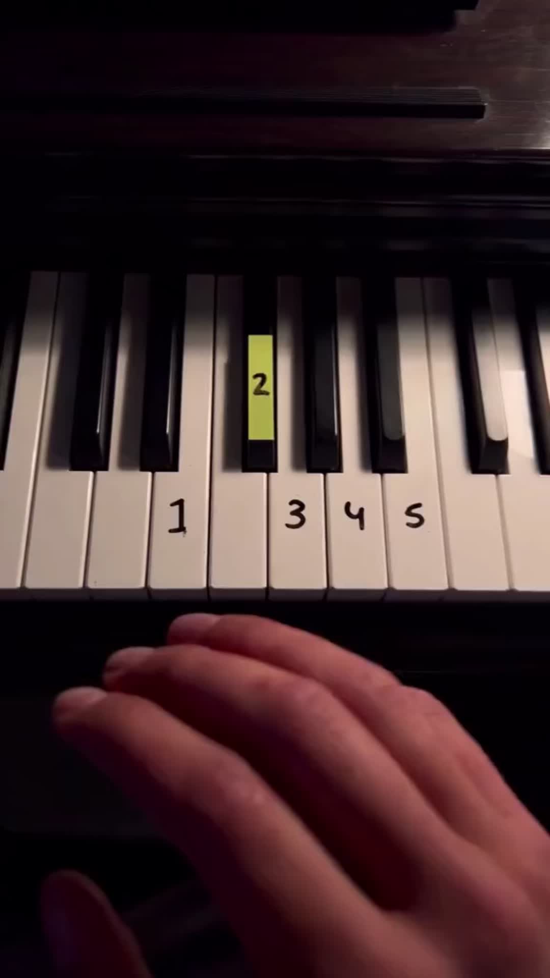 This may contain: a person's hand is playing the piano with yellow notes on it and black keys