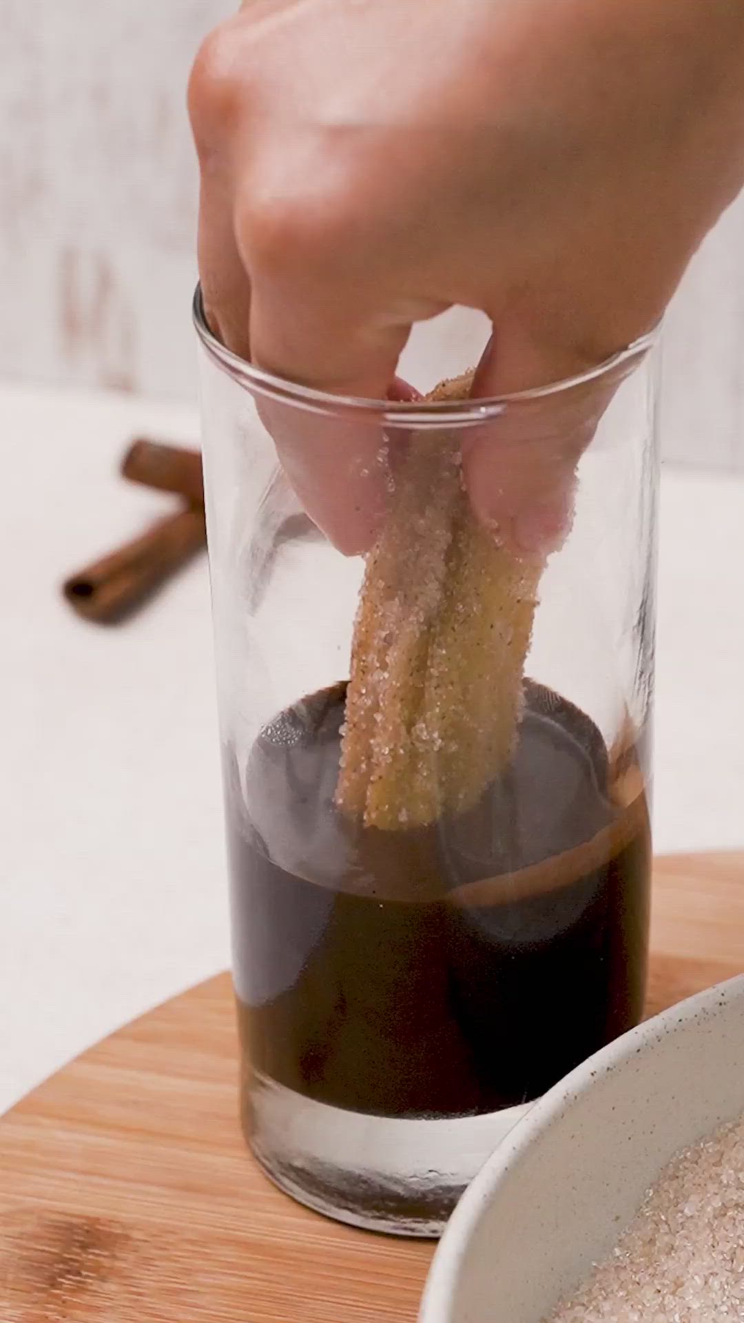 This may contain: a person dipping something into a glass with powdered sugar on the side and text gluten free churros