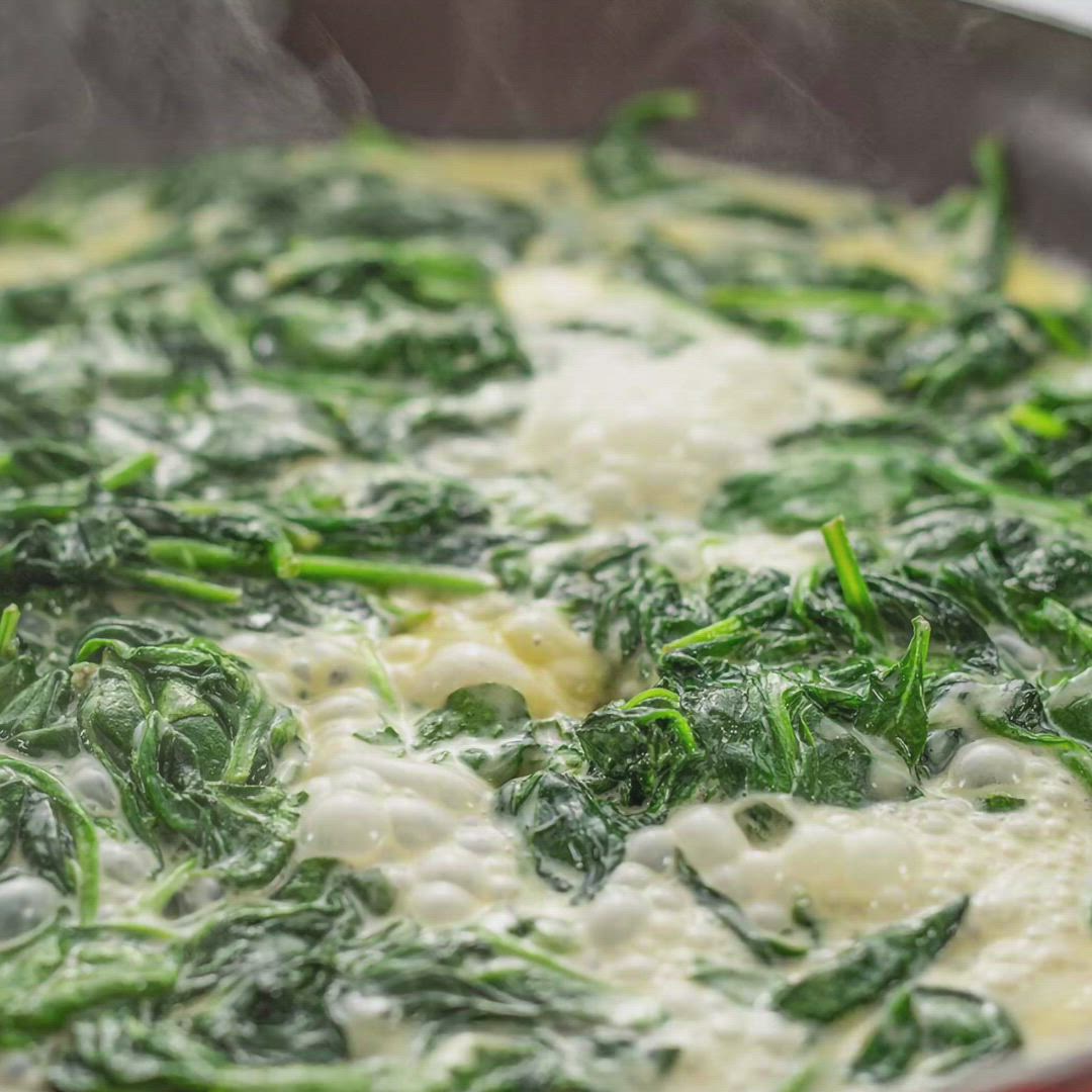 This may contain: spinach and cheese cooking in a skillet with steam rising from the top,