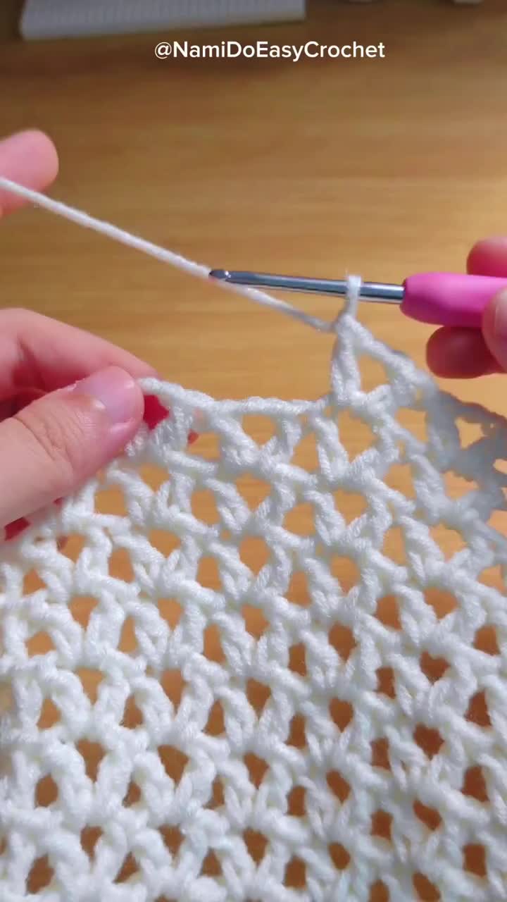 This may contain: someone crocheting the stitchs on a white piece of yarn