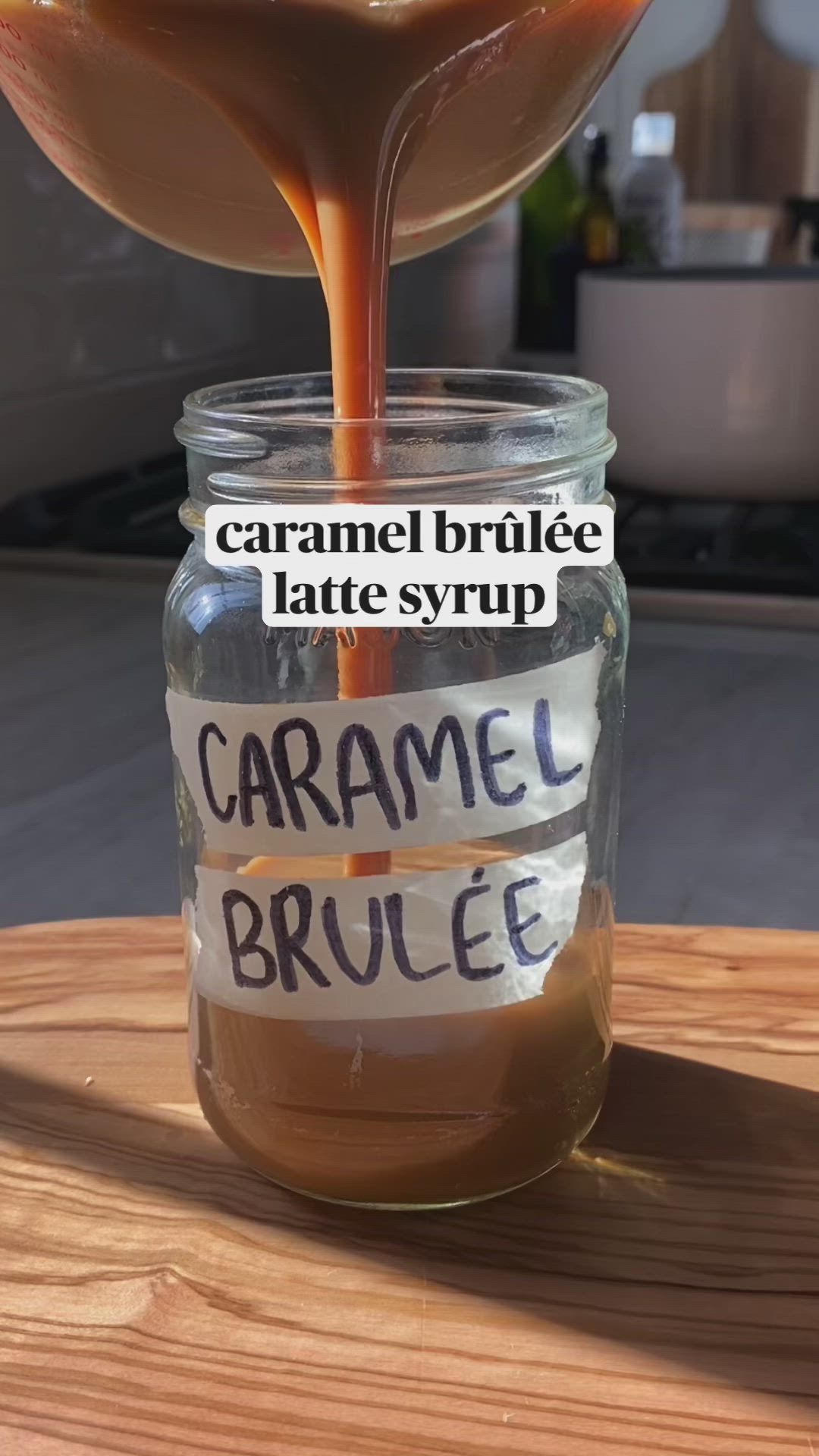 This may contain: caramel syrup being poured into a jar with labels on the inside and below it