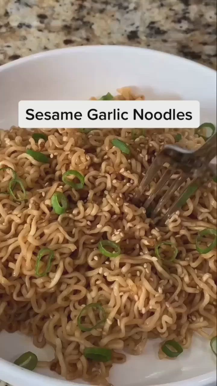 This may contain: a white bowl filled with sesame garlic noodles