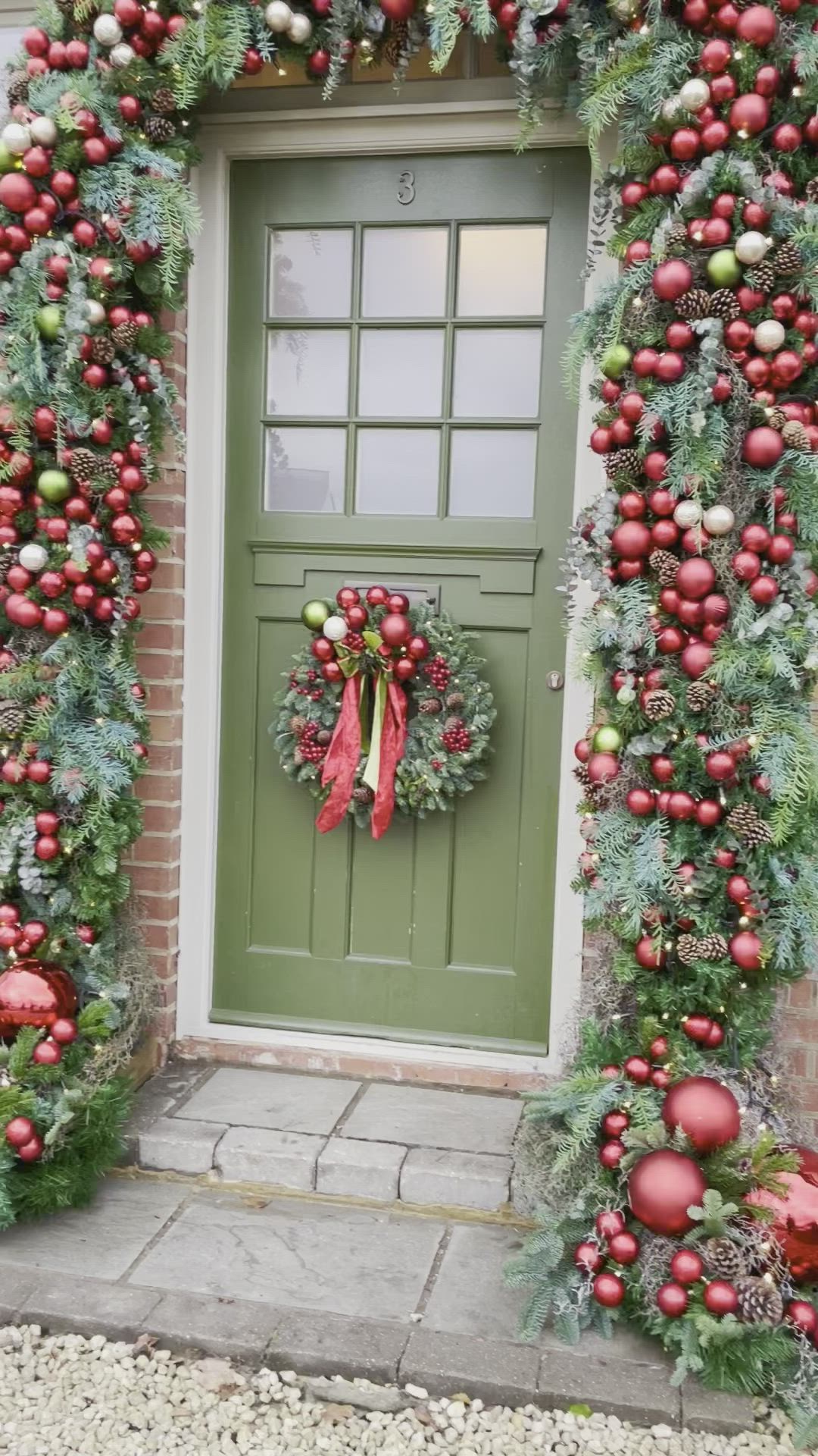 This may contain: a green door decorated with christmas wreaths and ornaments