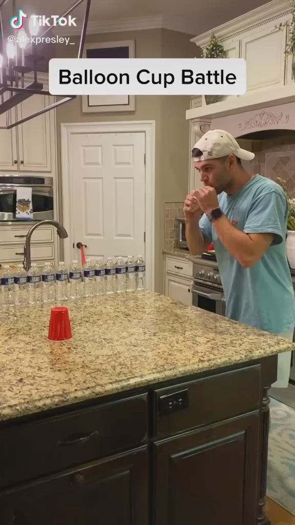 This may contain: a man standing in a kitchen next to an orange cone on top of a counter