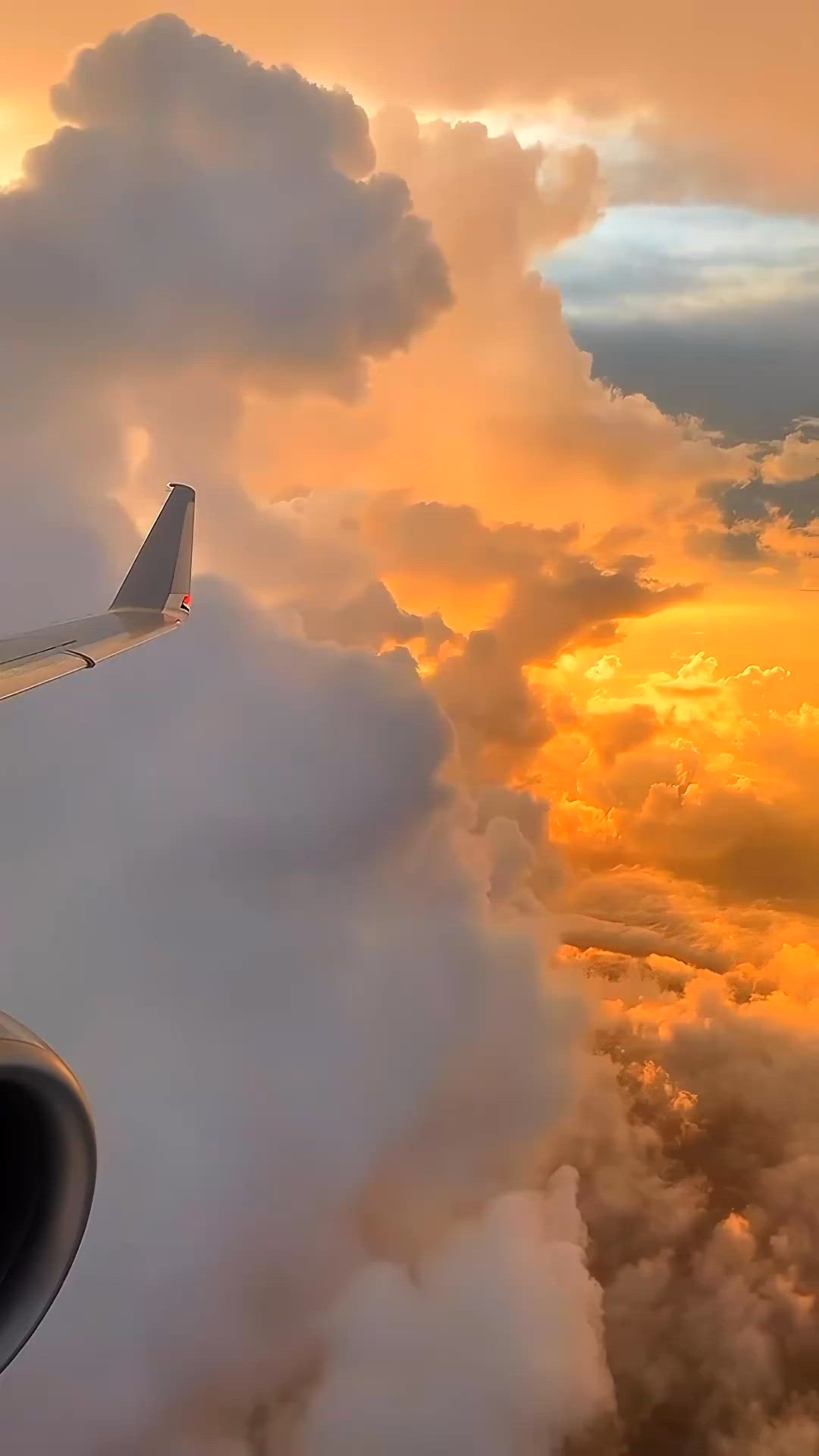 This may contain: an airplane wing flying through the clouds at sunset