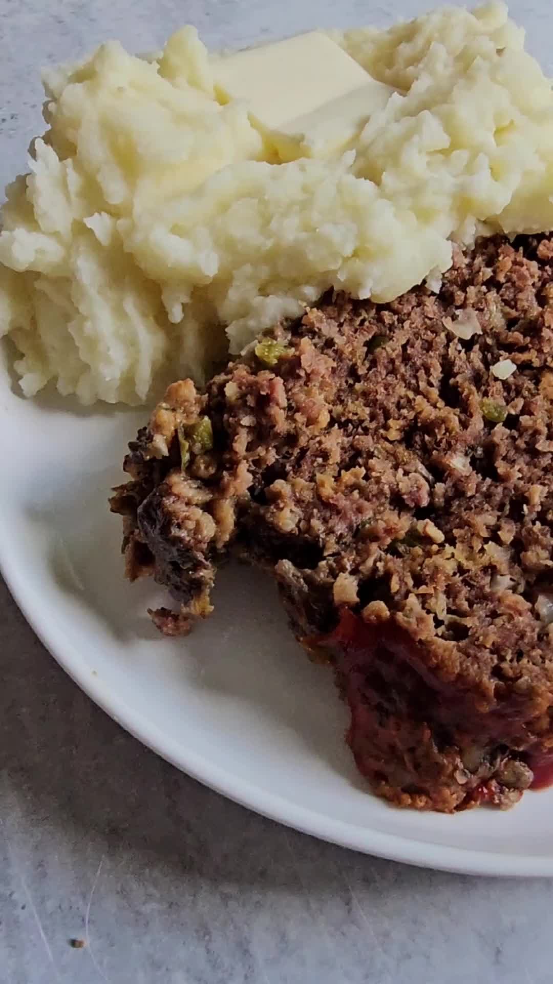 This may contain: meatloaf on a plate being cut with a knife