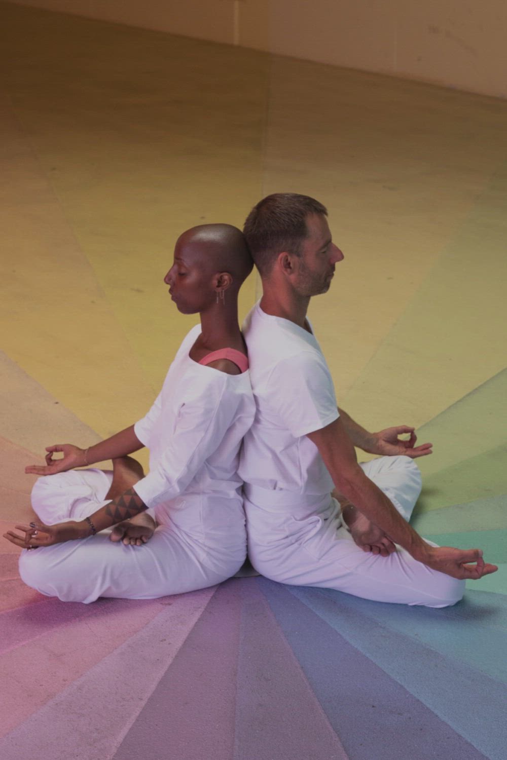 This may contain: two men sitting on the ground with their hands in each other's pockets, one man is doing yoga