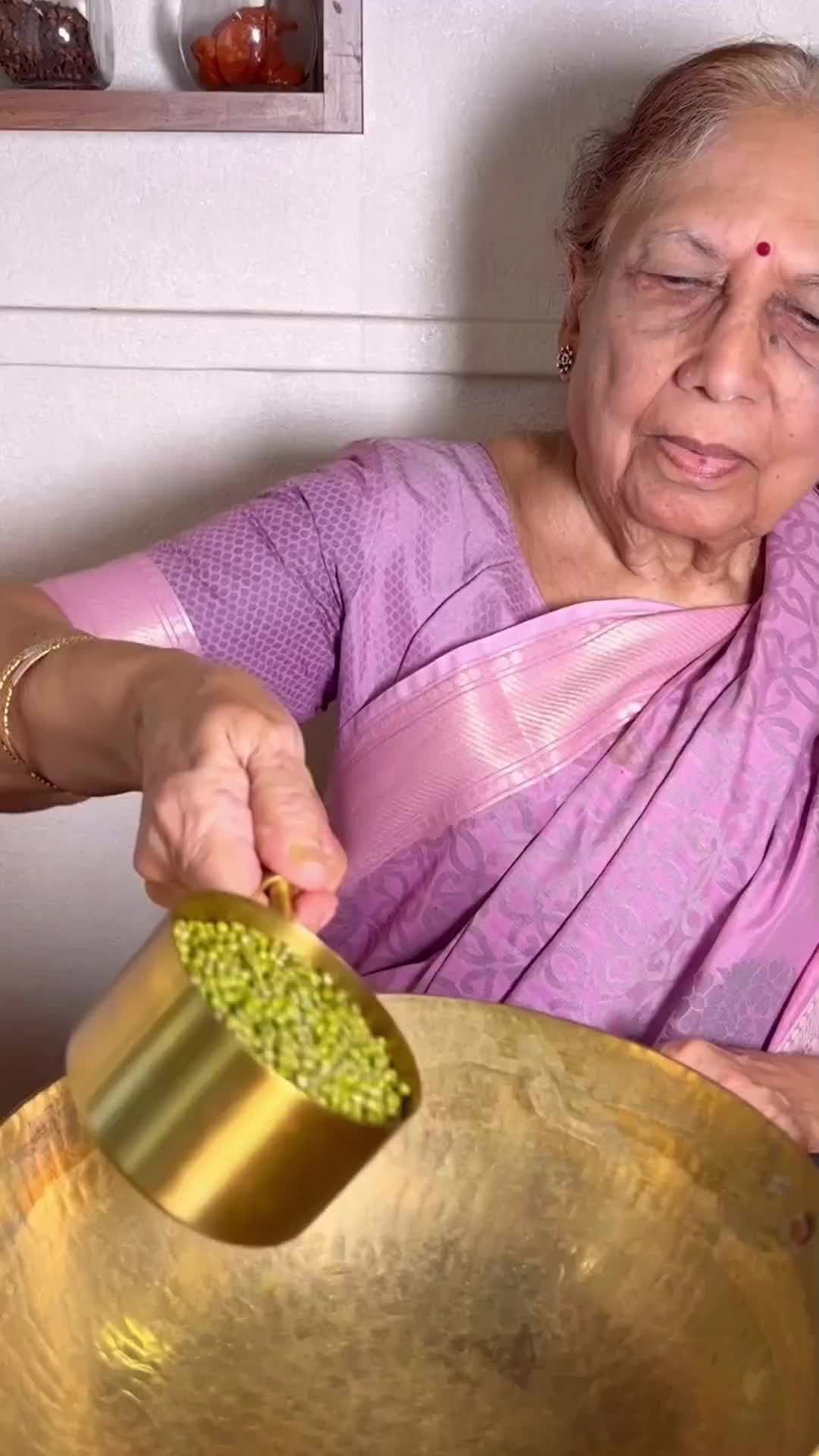 This may contain: an old woman holding a large metal bowl