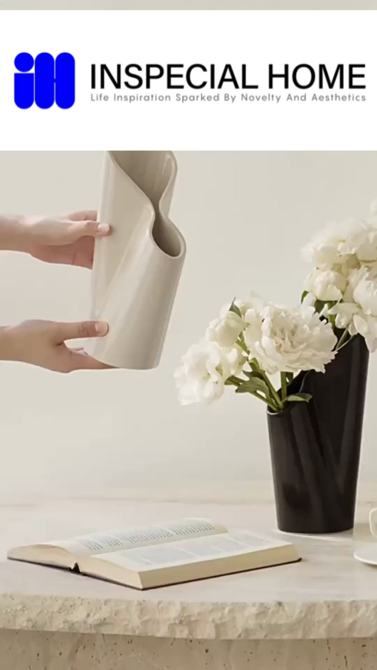 This may contain: a vase with white flowers and a book on a table