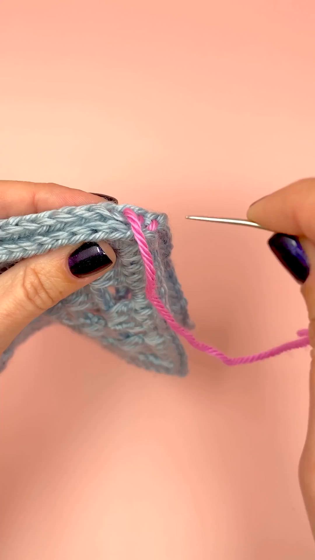 This may contain: two hands are holding yarn and knitting the end of a crochet piece with needles