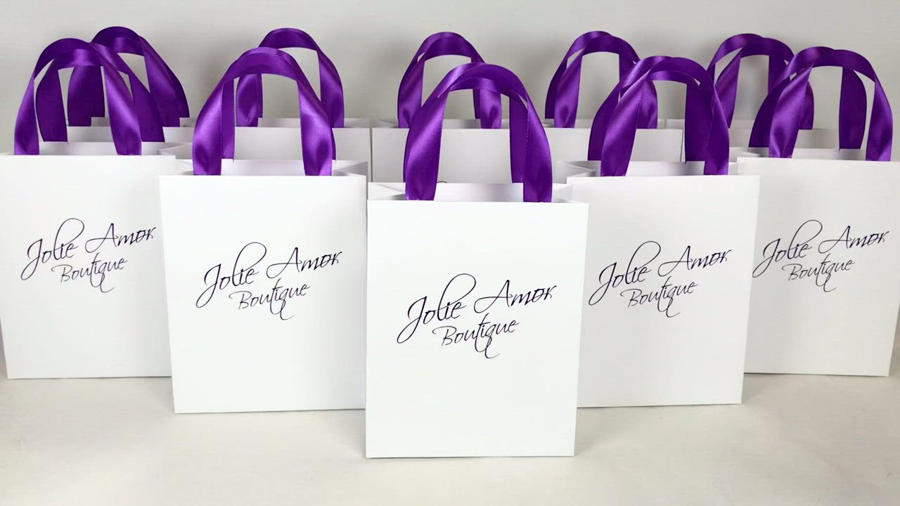 This may contain: six white bags with purple ribbons on them