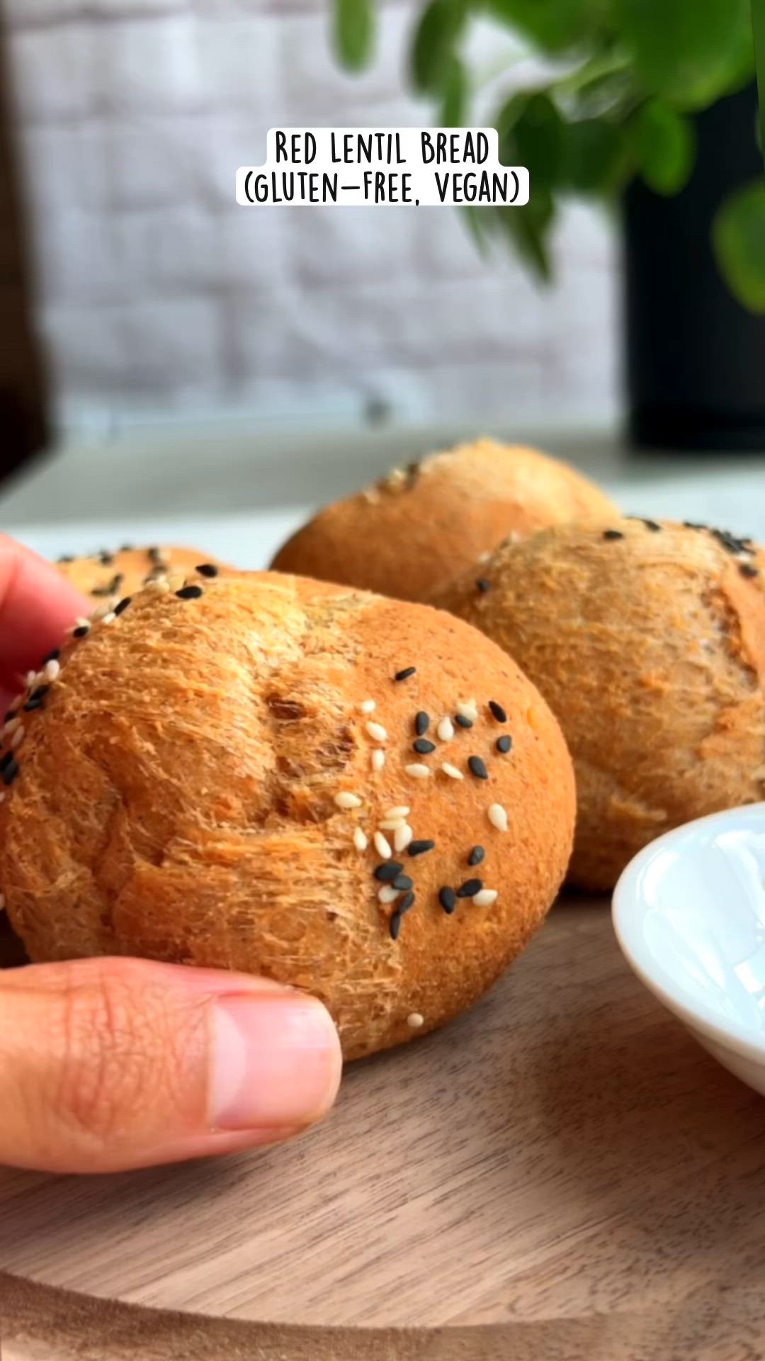 This may contain: a person is holding some bread on a wooden board next to a bowl with sesame seeds