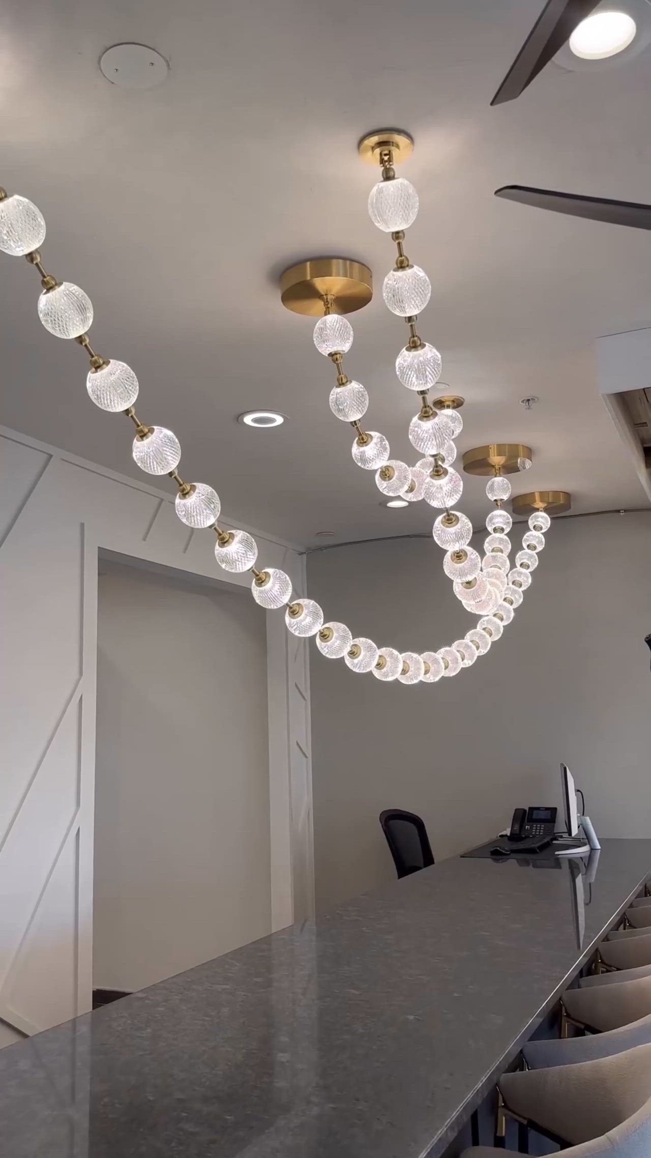 This may contain: a long table with chairs and lights hanging from it's ceiling in an office