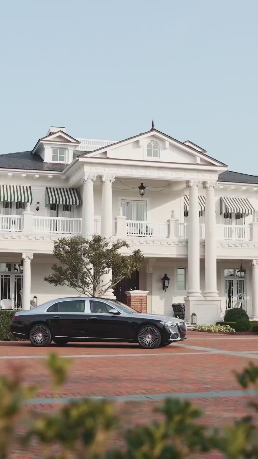 This may contain: two black cars parked in front of a large white building with columns and balconies