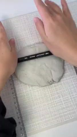 This may contain: a person is using a pencil to draw on a marble object with white paper and black marker