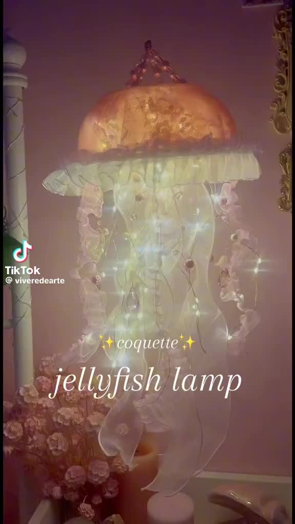 This may contain: a lighted jellyfish lamp in the corner of a room with flowers and candles around it