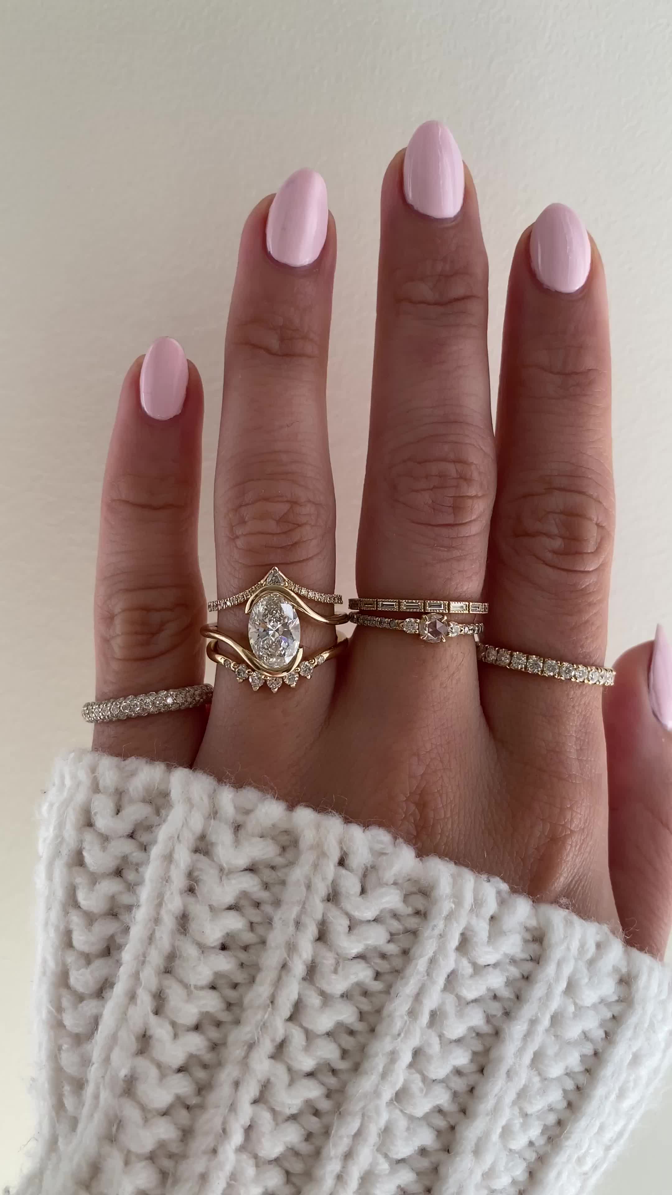 This may contain: a woman's hand with three different rings on her fingers and one is wearing a sweater