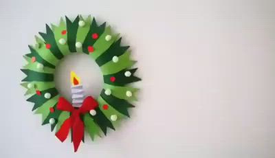 This may contain: a paper wreath with a lit candle on it