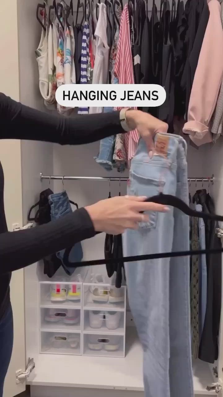 This may contain: two women are trying to hang jeans in the closet