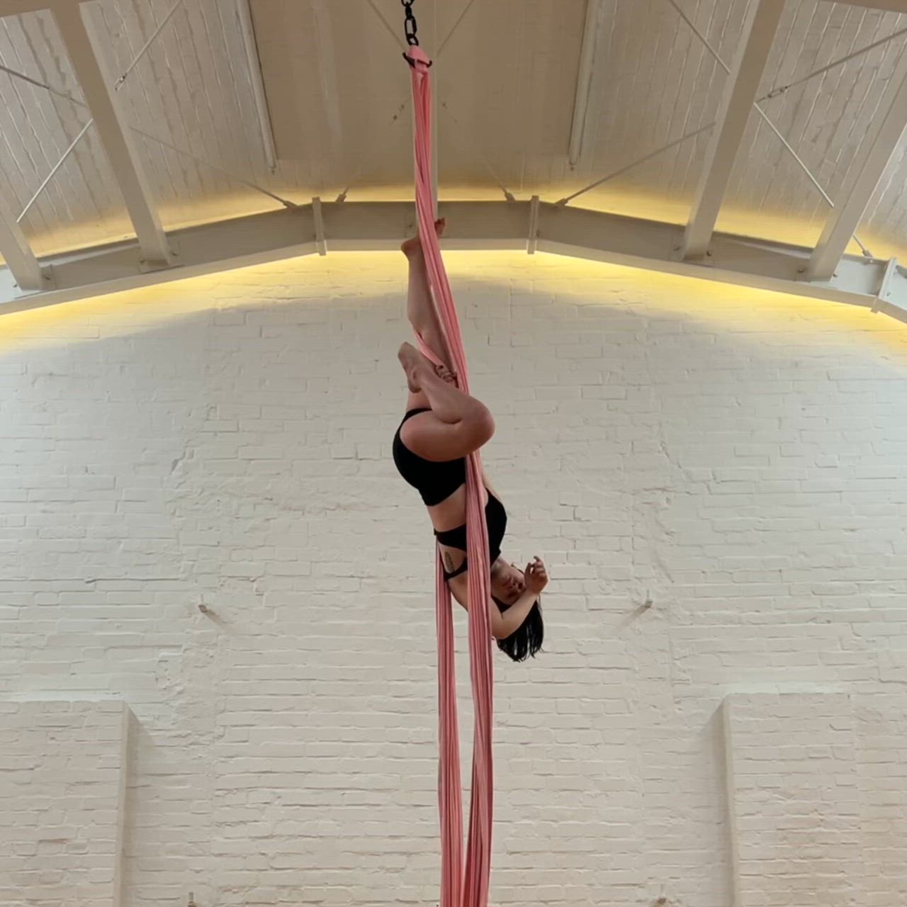 This may contain: a woman is performing aerial acrobatic tricks on a pole