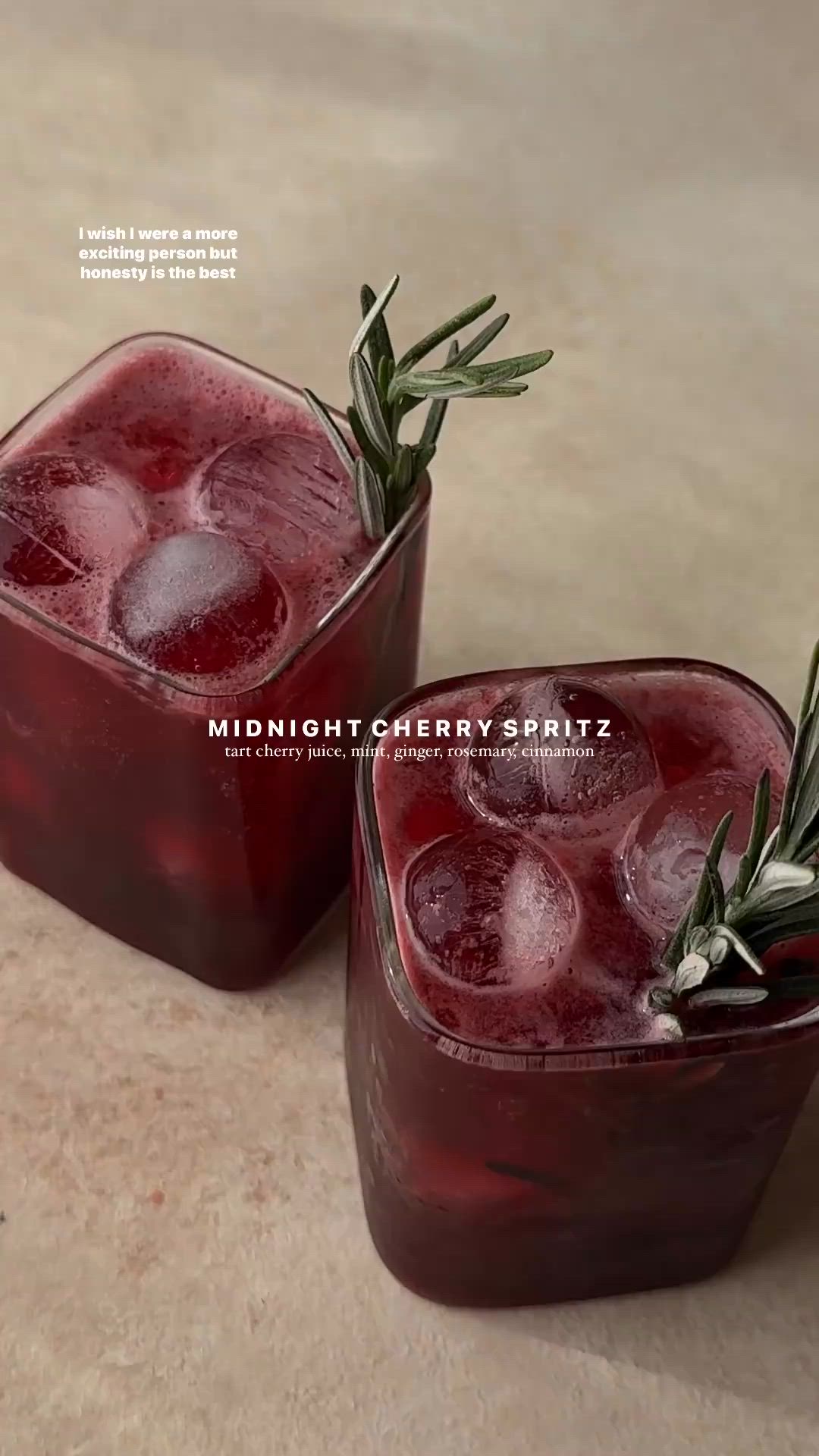 This may contain: two glasses filled with red liquid and garnished with rosemary