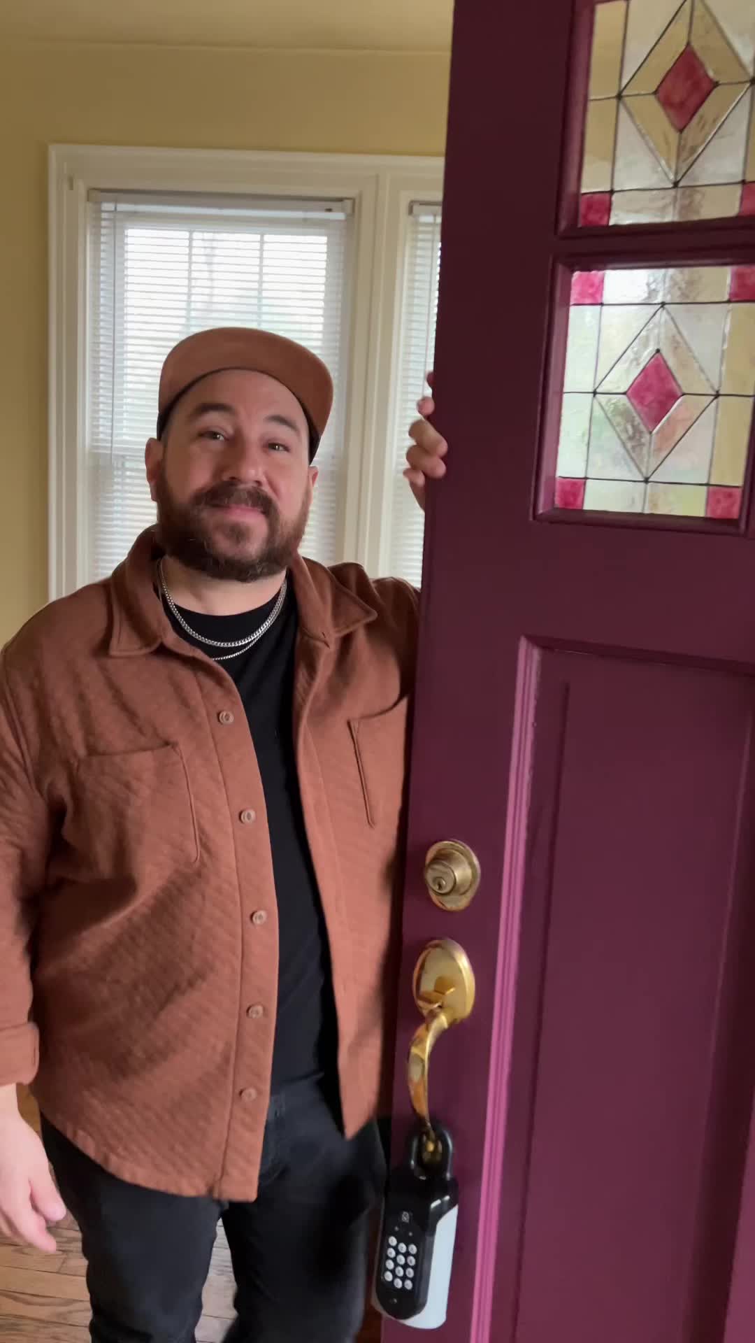 This may contain: a person holding up a stained glass window in front of a purple door with pink trim