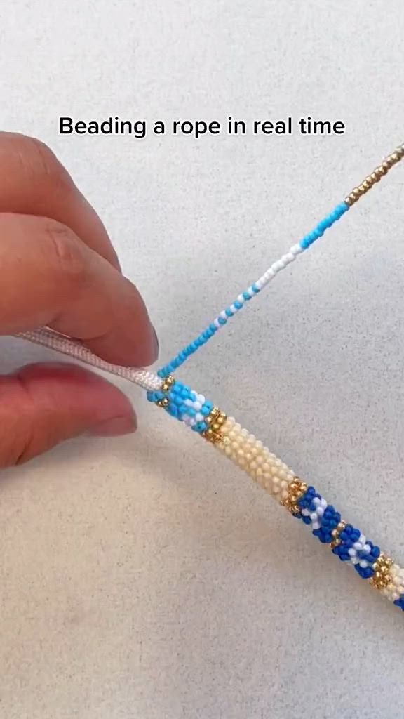 This may contain: a person is making beading a rope in real time with beads and thread on the end