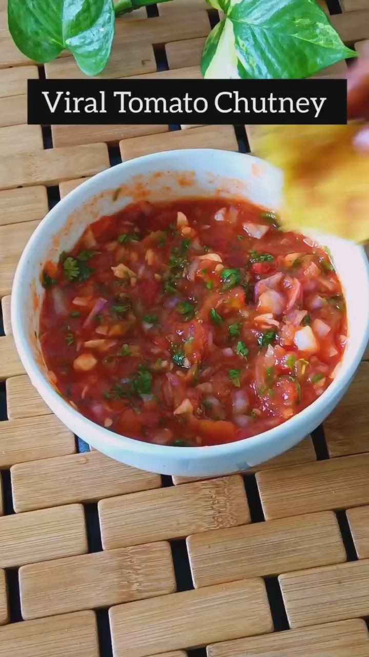 This may contain: a close up of a bowl of food on a table with basil and tomatoes in the background