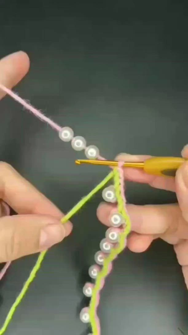 This may contain: two hands crocheting beads on a string