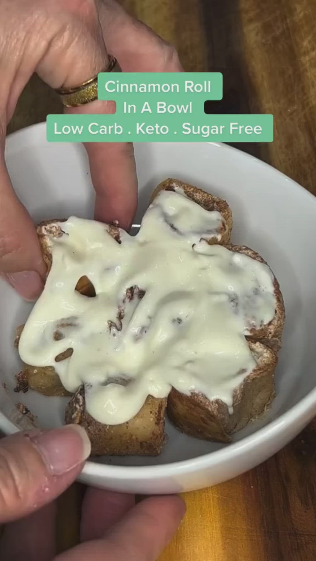 This may contain: two pieces of bread in a bowl with white icing on top and cinnamon roll in the middle