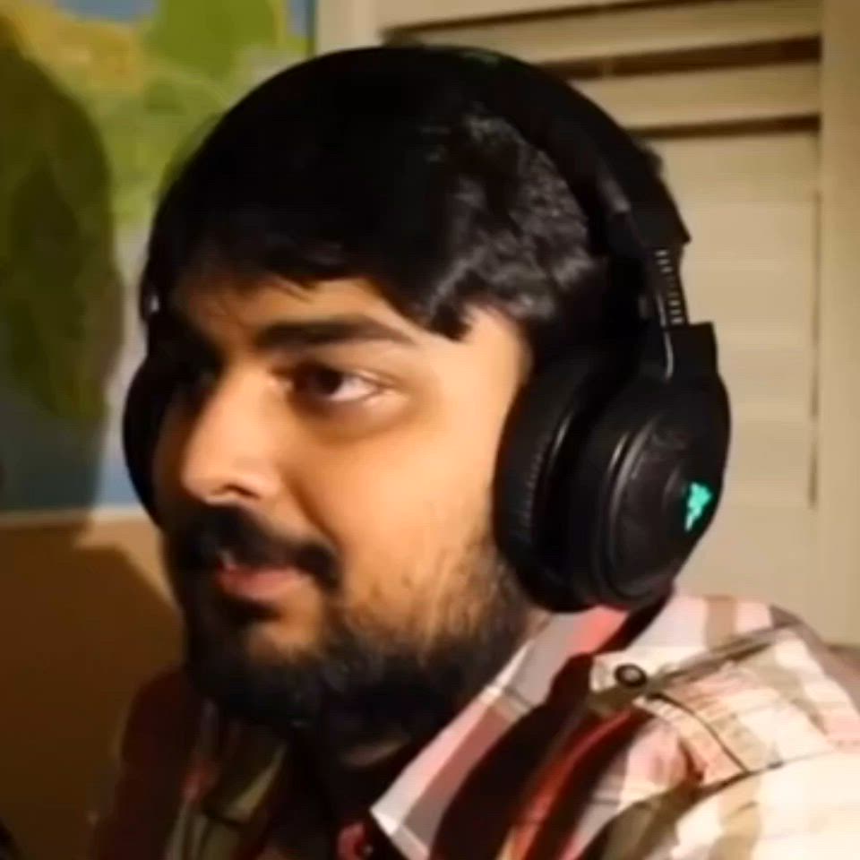 This may contain: a man wearing headphones while sitting in front of a computer