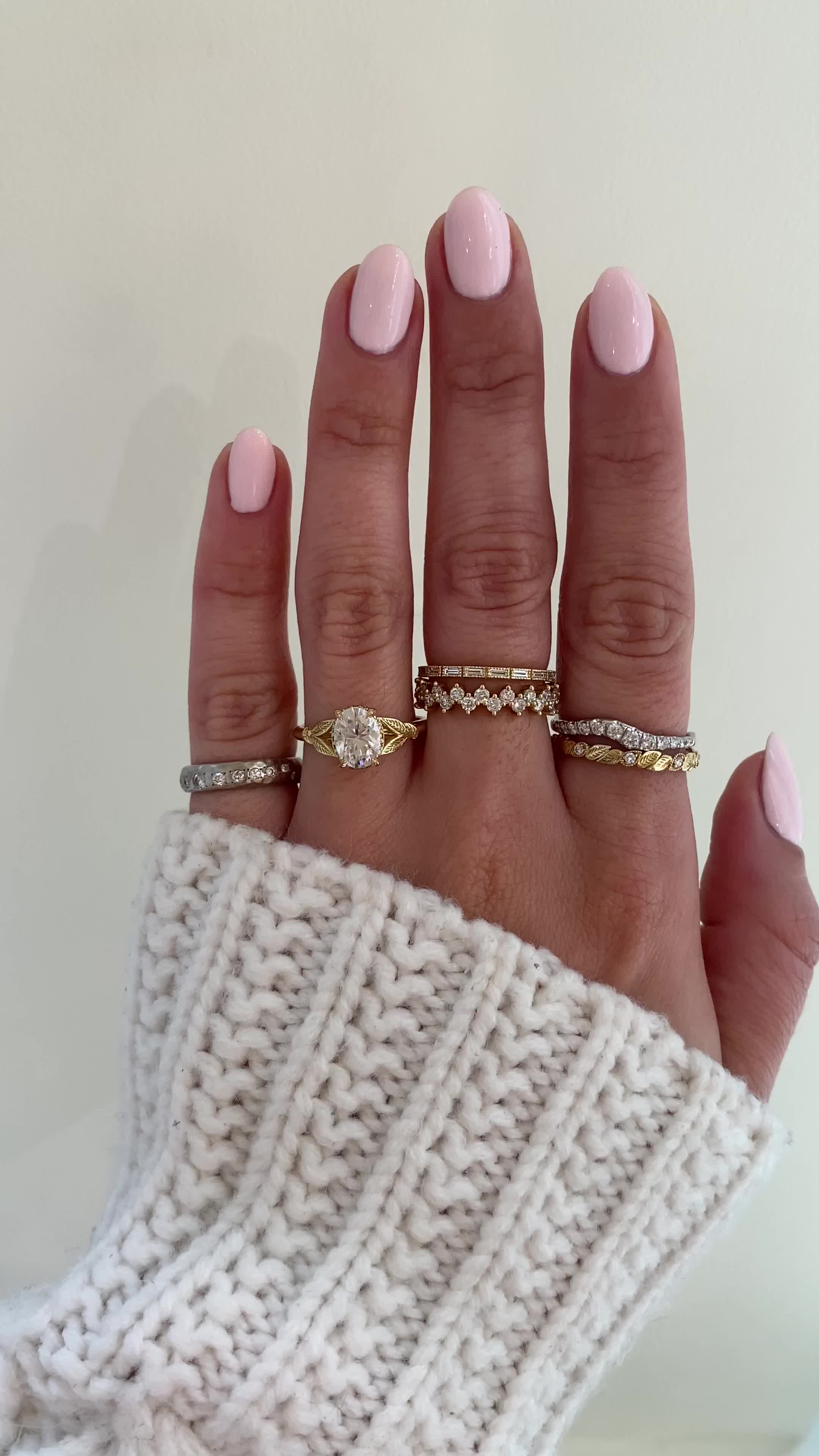 This may contain: a woman's hand with three different rings on her fingers and one is wearing a sweater