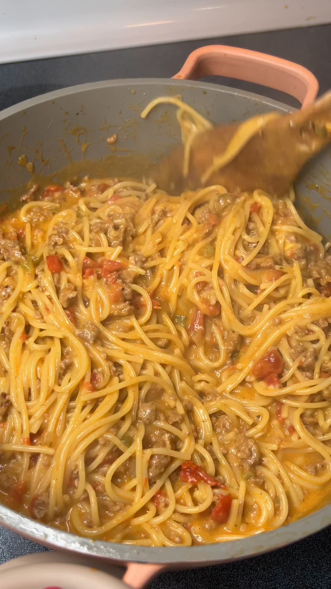 This may contain: a spoon full of spaghetti with meat and vegetables in it on top of a pan