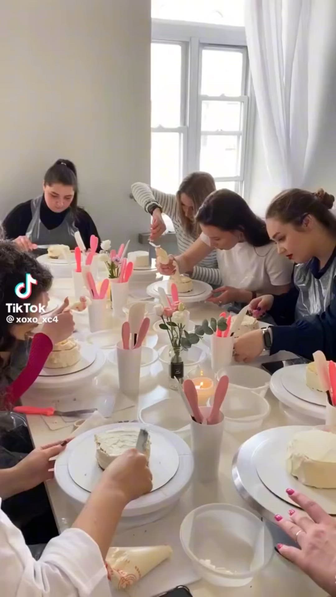 This may contain: a group of people sitting around a table eating cake