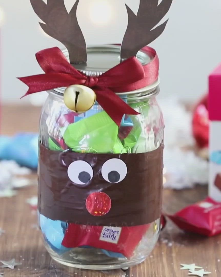 This may contain: a glass jar filled with candy and reindeer decorations