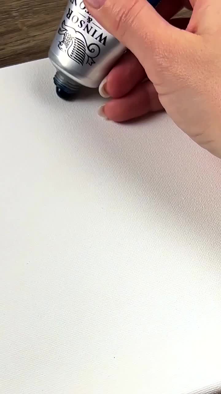 This may contain: a person using a spray can to paint a piece of white paper on a table