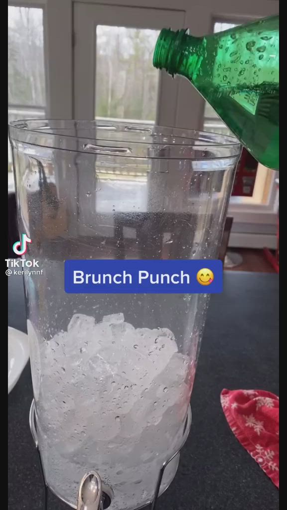 This may contain: a glass filled with ice sitting on top of a counter next to a green bottle