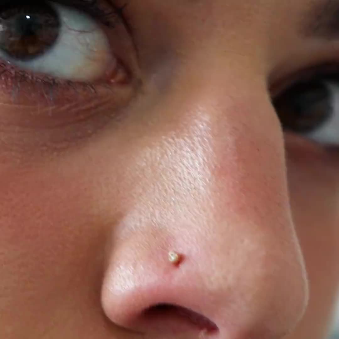 This may contain: a close up of a woman's nose with piercing on her left cheek and right eye