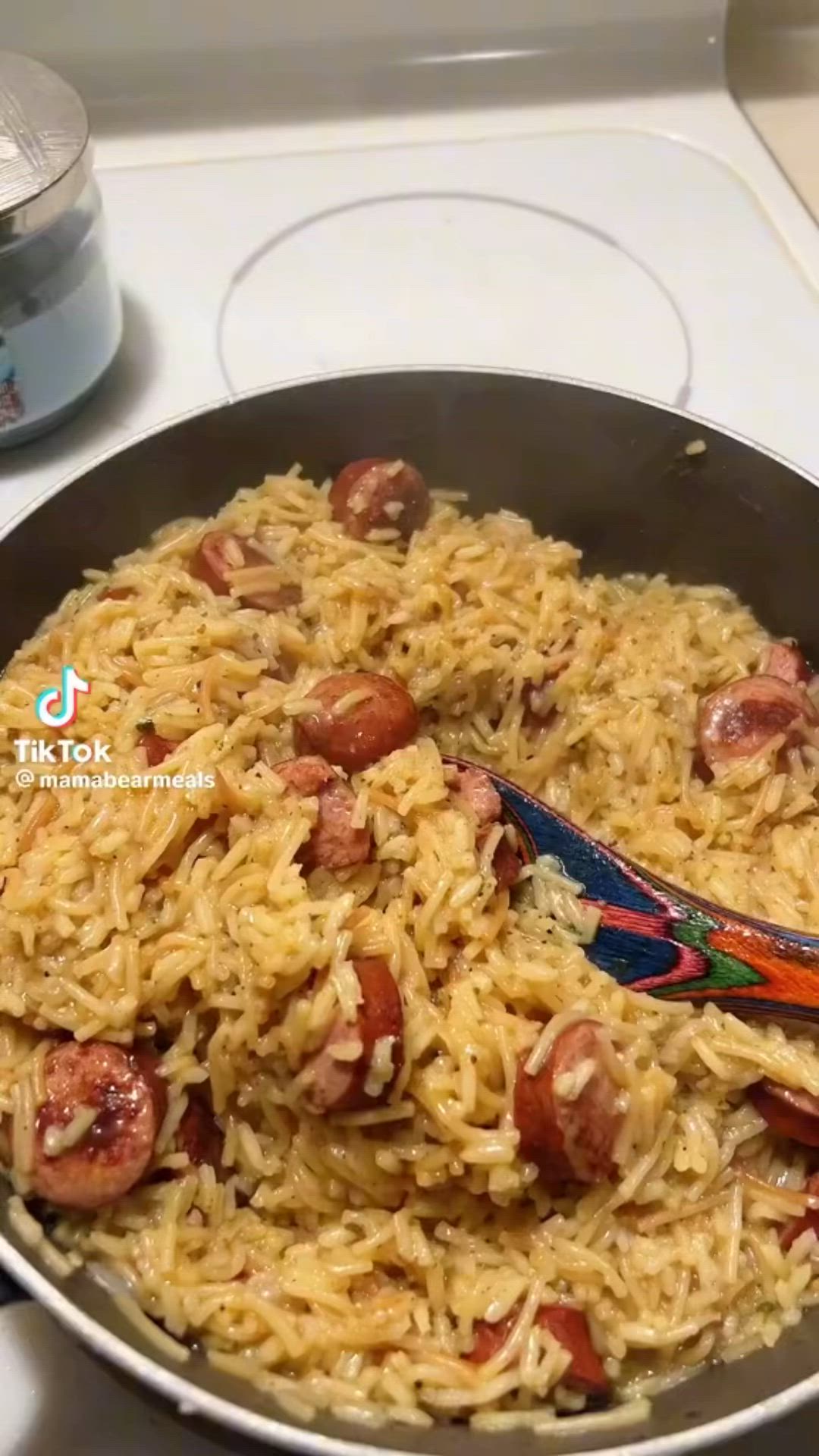 This may contain: a pan filled with rice and sausage on top of a stove