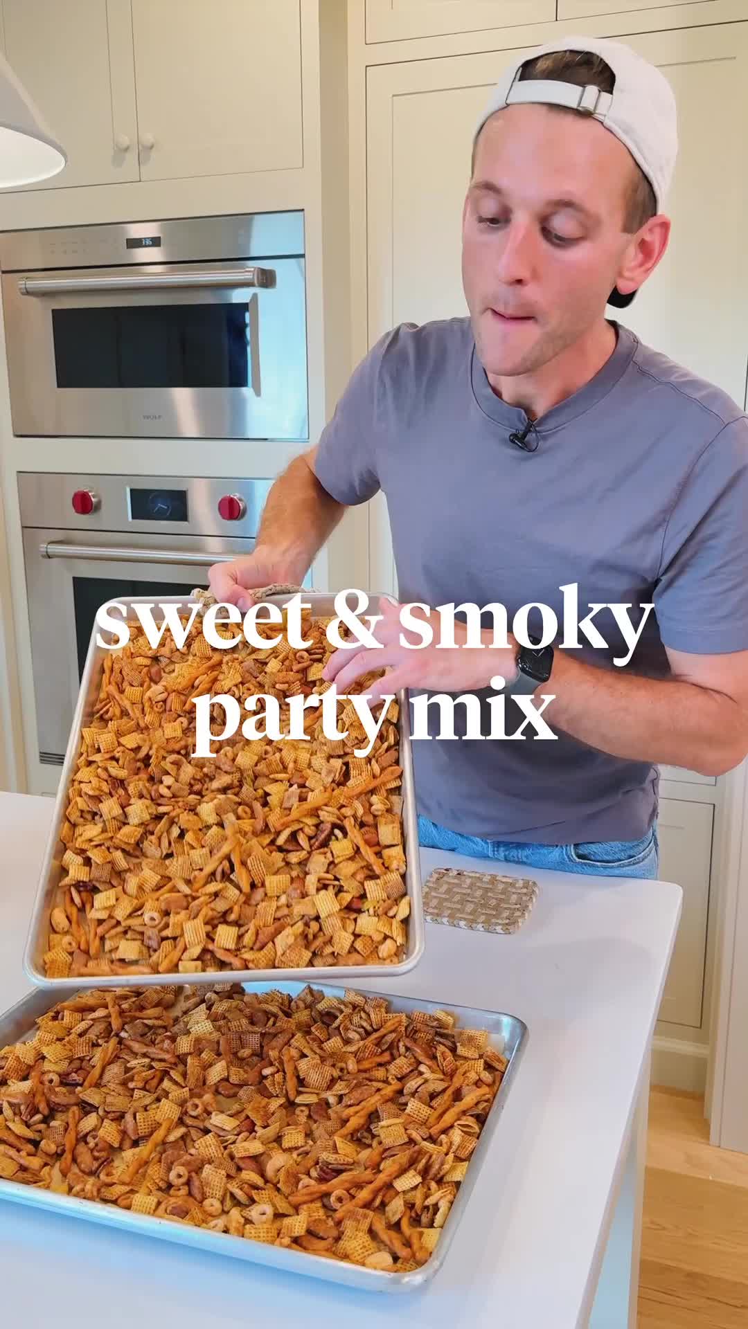 This may contain: a man holding a pan filled with sweet and smoky party mix