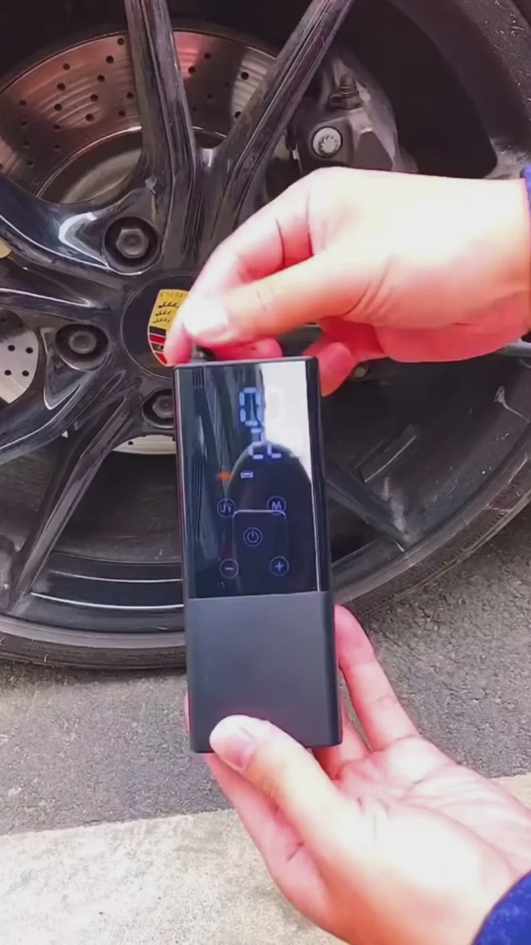 This may contain: a person holding a cell phone in front of a car tire with the screen on it