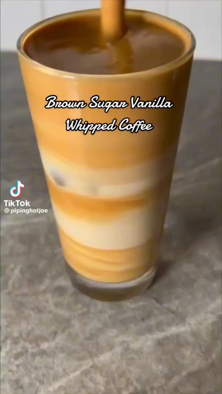 This may contain: a cup that is sitting on top of a table with the words brown sugar vanilla whipped coffee