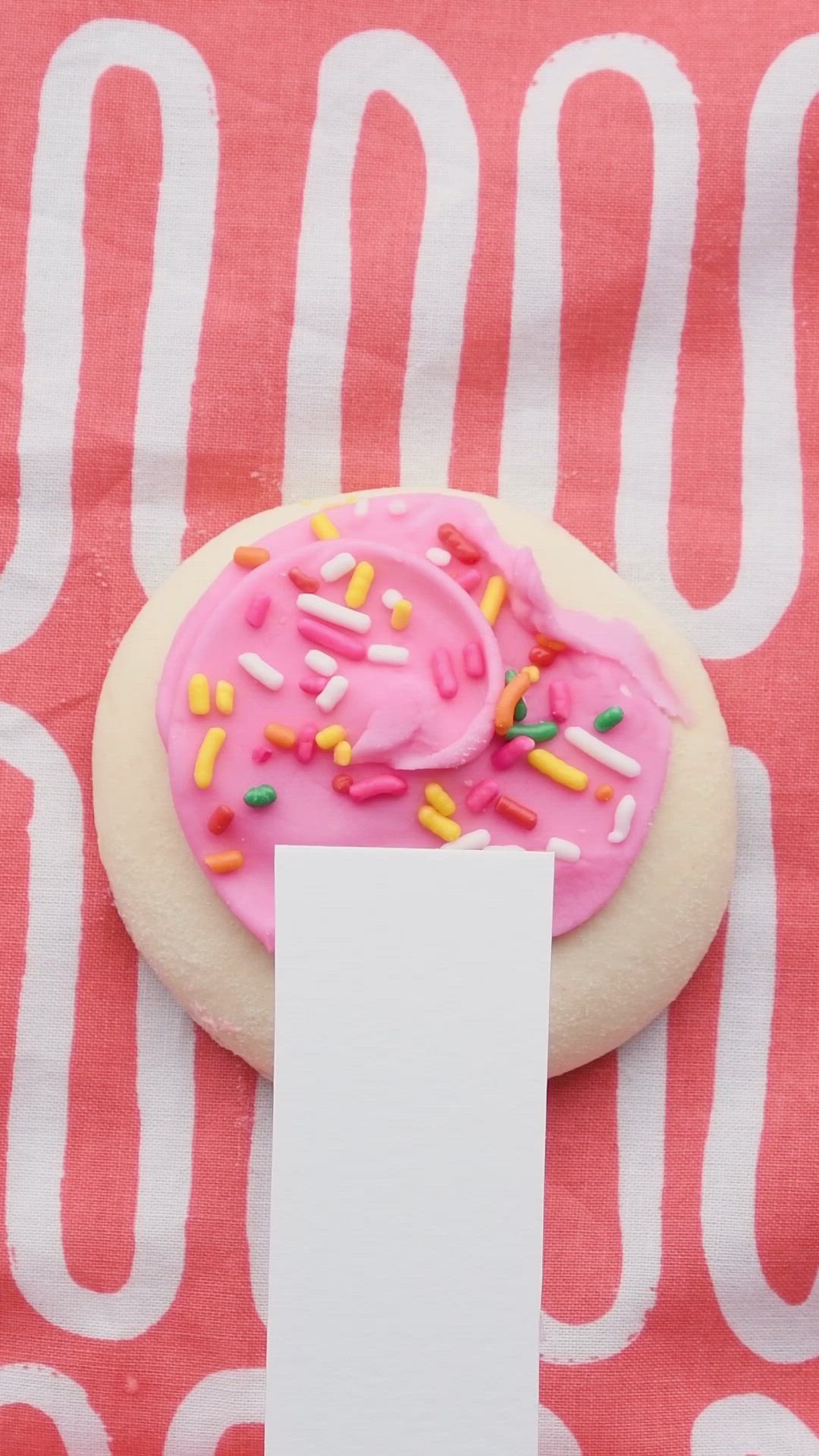 This may contain: a pink frosted doughnut with sprinkles and a blank card