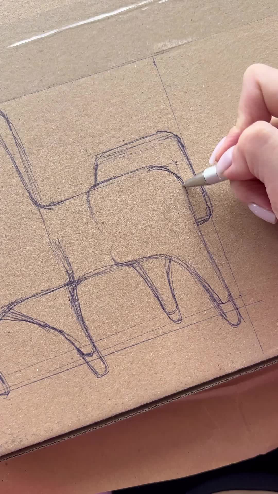 This may contain: someone drawing a chair with a pencil on top of a piece of cardboard that is sitting on a table